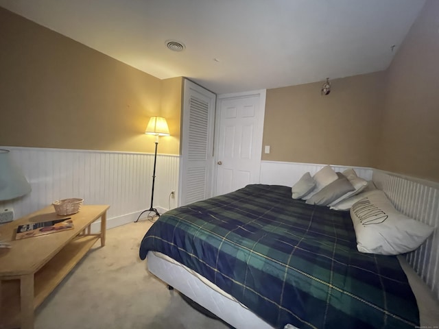 carpeted bedroom with visible vents and wainscoting