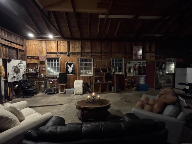 living room with wood walls, washer / clothes dryer, and unfinished concrete flooring