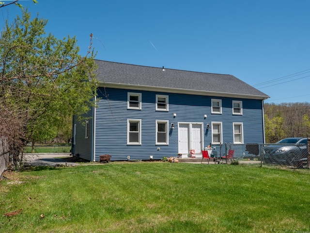 rear view of property with a lawn and fence