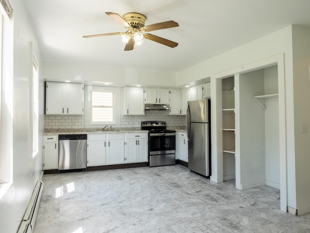 kitchen with decorative backsplash, ceiling fan, a baseboard heating unit, under cabinet range hood, and appliances with stainless steel finishes
