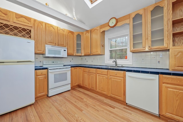 kitchen with a sink, decorative backsplash, light wood finished floors, and white appliances