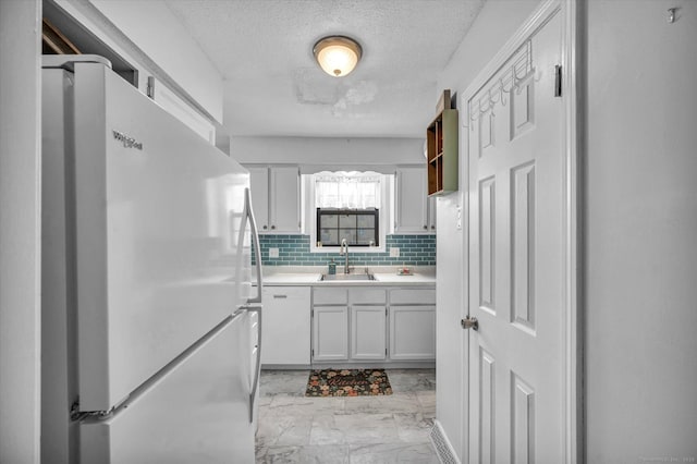 kitchen with light countertops, white appliances, decorative backsplash, marble finish floor, and a sink