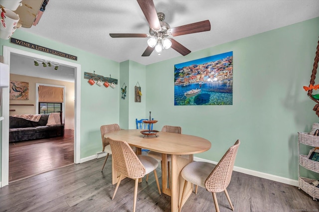 dining area with baseboards, wood finished floors, ceiling fan, and a textured ceiling