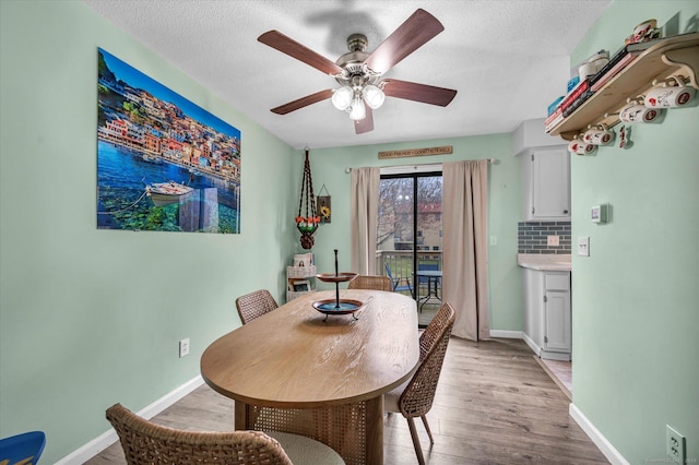 dining area with a ceiling fan, a textured ceiling, baseboards, and light wood-type flooring