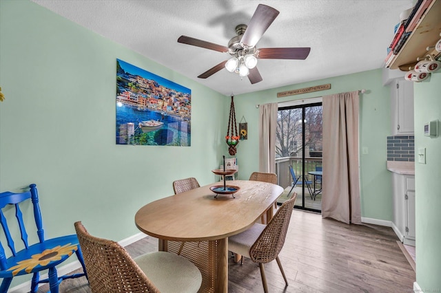 dining area featuring baseboards, a textured ceiling, ceiling fan, and light wood finished floors