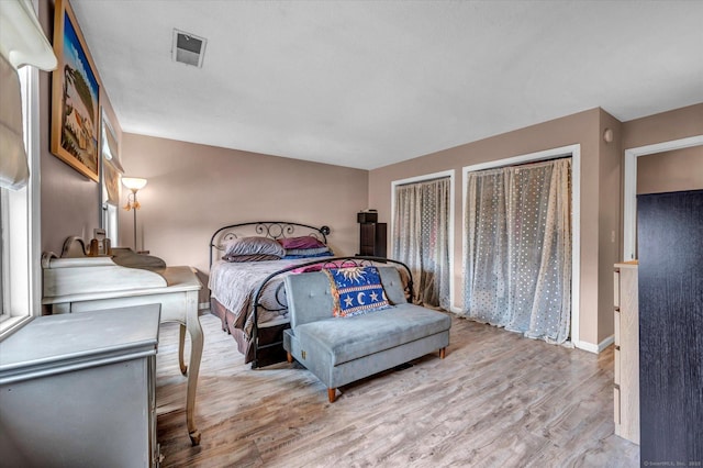 bedroom featuring baseboards, visible vents, and light wood finished floors
