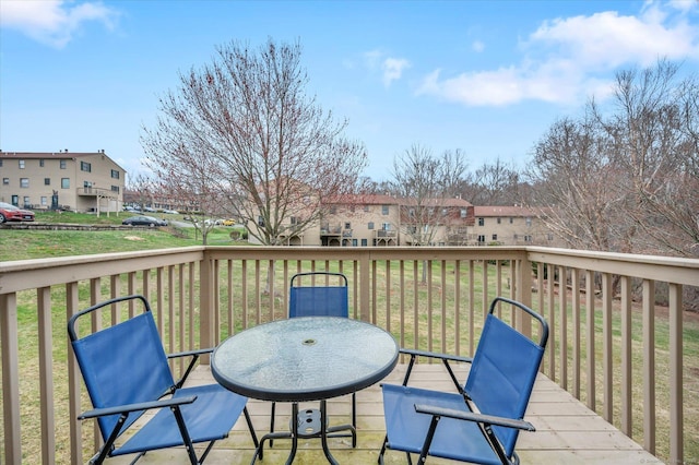 deck featuring outdoor dining space, a yard, and a residential view