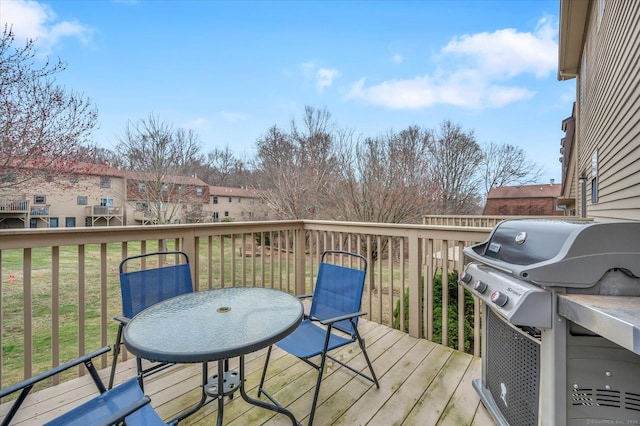 wooden terrace featuring outdoor dining space, area for grilling, and a yard