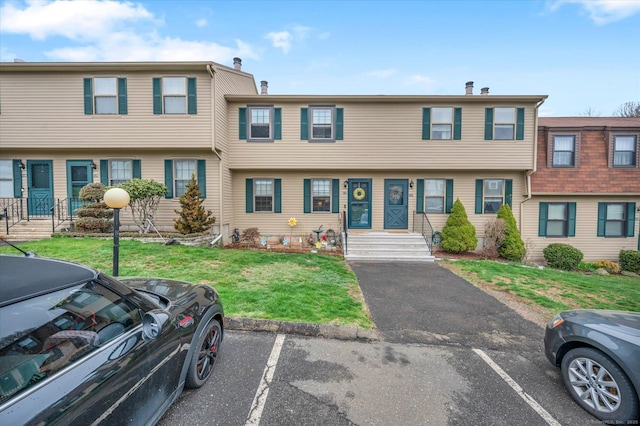 view of property featuring uncovered parking and a front yard