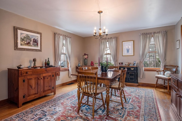 dining space with a wealth of natural light, light wood finished floors, an inviting chandelier, and baseboards