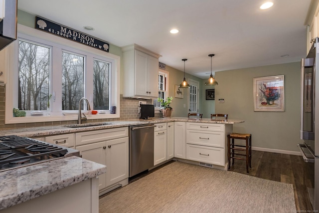 kitchen featuring light wood-style floors, a sink, backsplash, and appliances with stainless steel finishes
