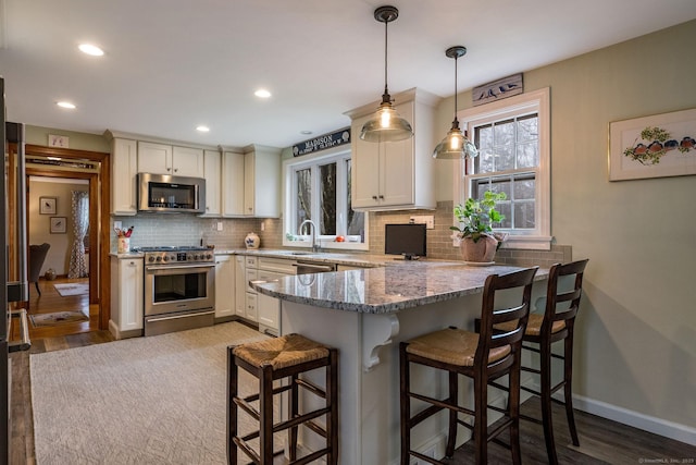 kitchen featuring a wealth of natural light, tasteful backsplash, a peninsula, and appliances with stainless steel finishes
