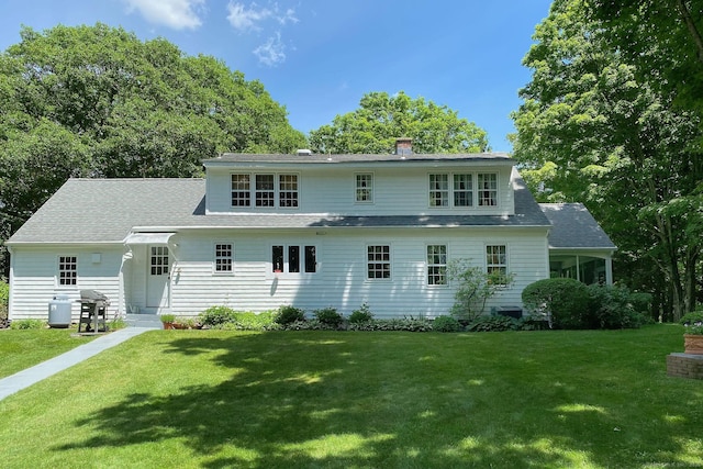 rear view of house with a yard and a shingled roof