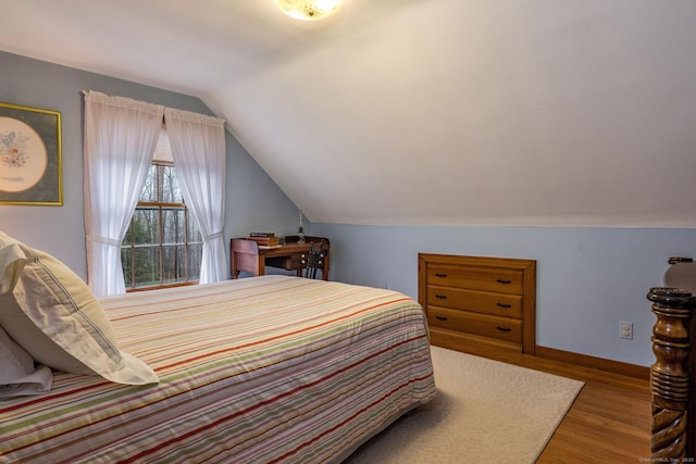 bedroom featuring wood finished floors, baseboards, and vaulted ceiling