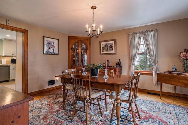 dining space with a notable chandelier, baseboards, and light wood-style flooring