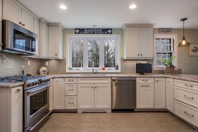 kitchen featuring a sink, appliances with stainless steel finishes, pendant lighting, light stone countertops, and decorative backsplash