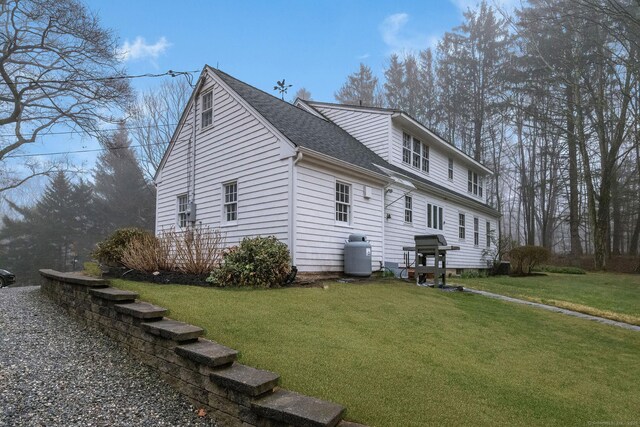 view of property exterior with a yard and roof with shingles