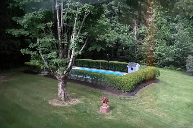 view of home's community featuring an outbuilding, a swimming pool, a storage shed, and a lawn