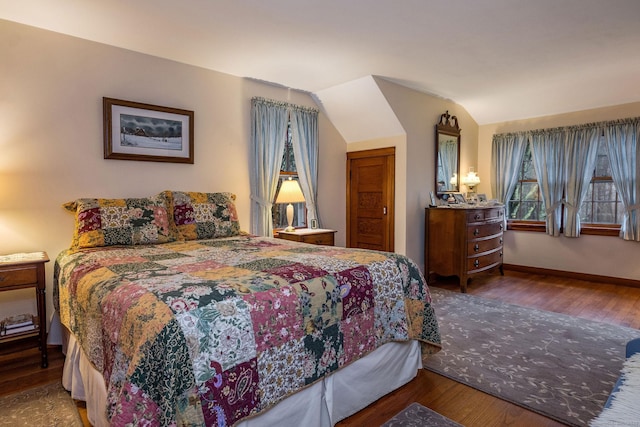 bedroom with wood finished floors, baseboards, and vaulted ceiling