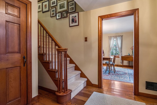 stairs with visible vents, baseboards, and hardwood / wood-style flooring