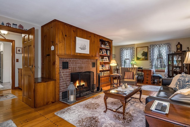 living room featuring light wood-type flooring, visible vents, and a brick fireplace