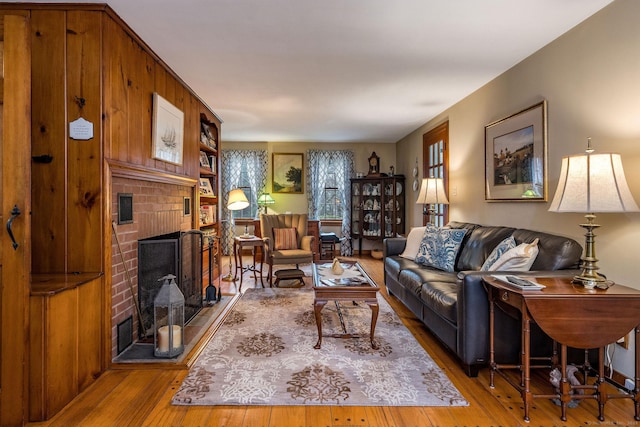 living room featuring visible vents, hardwood / wood-style flooring, and a brick fireplace