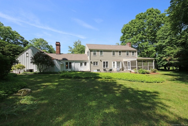 125 Silver Spring Rd, Fairfield, CT 06824 - rear view of house with a sunroom, a chimney, and a lawn