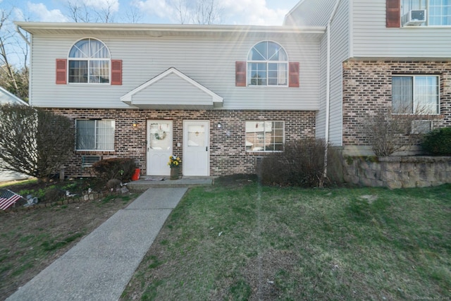 view of front facade with brick siding and a front lawn