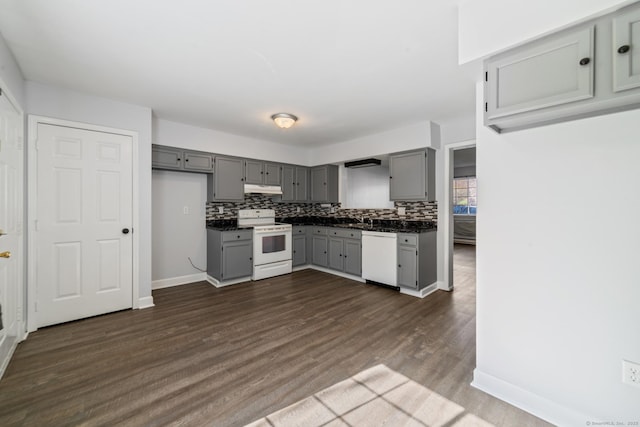 kitchen with tasteful backsplash, white appliances, dark wood finished floors, under cabinet range hood, and gray cabinetry