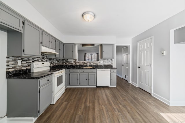 kitchen with white appliances, dark wood-style floors, gray cabinets, under cabinet range hood, and backsplash