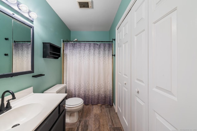 bathroom with visible vents, a shower with curtain, toilet, wood finish floors, and vanity