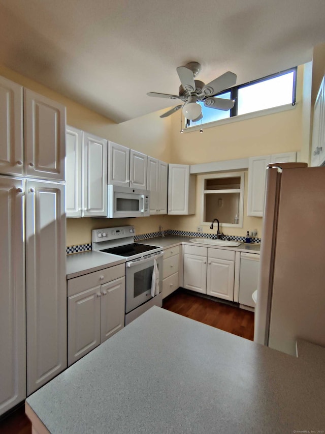 kitchen with white cabinetry, lofted ceiling, white appliances, a sink, and a ceiling fan
