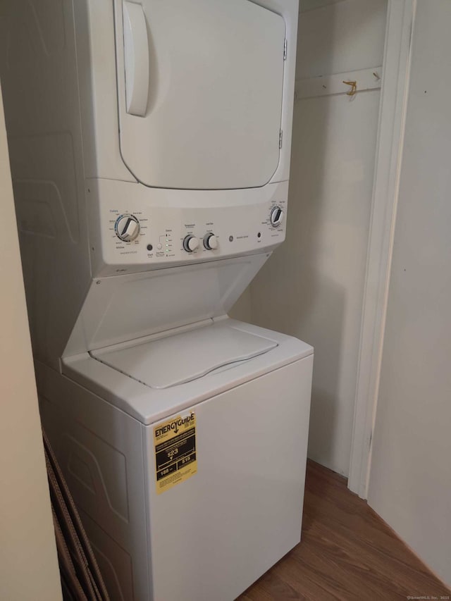 clothes washing area with stacked washing maching and dryer, laundry area, and dark wood finished floors