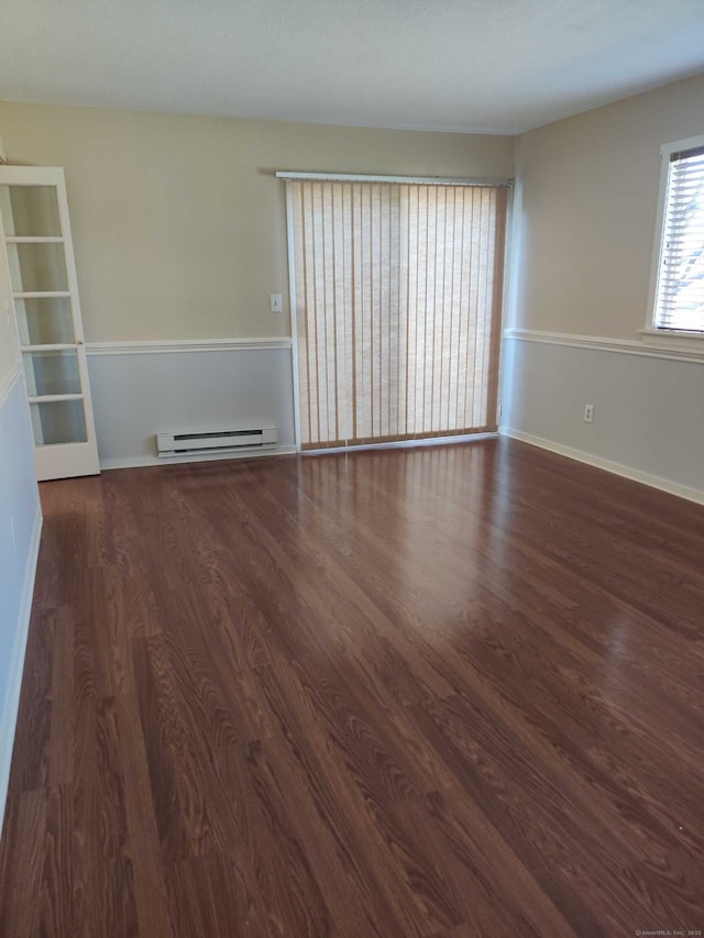 empty room with baseboards, a baseboard heating unit, and wood finished floors