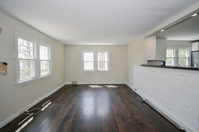 unfurnished living room with visible vents, dark wood finished floors, and baseboards