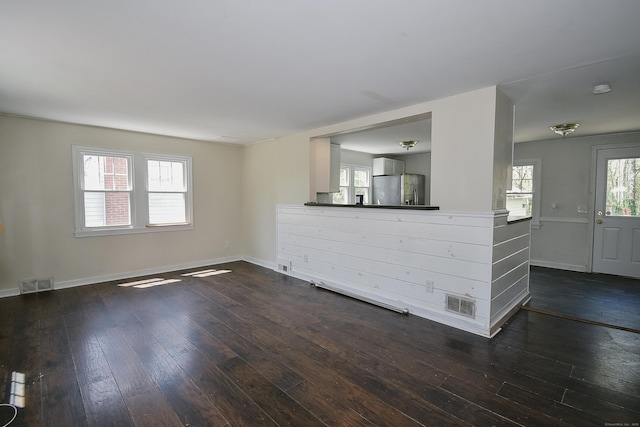unfurnished living room with baseboards, dark wood-style floors, and visible vents