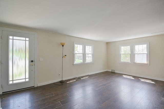 unfurnished living room featuring visible vents, baseboards, a wealth of natural light, and dark wood-style floors