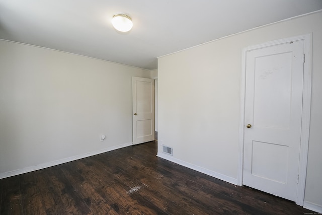 spare room with visible vents, baseboards, crown molding, and dark wood-style floors