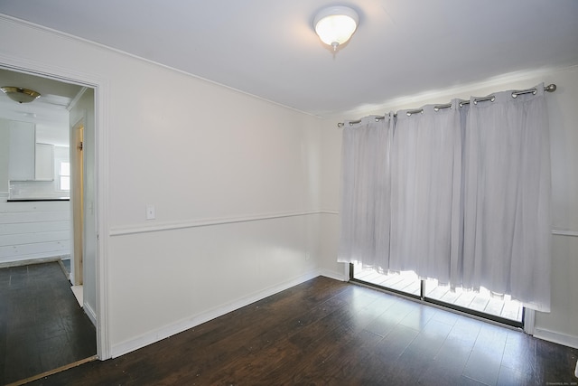 spare room with crown molding, dark wood-style flooring, and baseboards