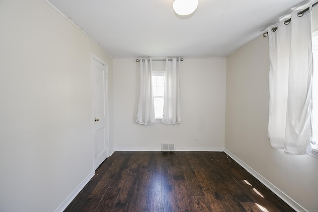 empty room featuring baseboards, visible vents, and wood finished floors