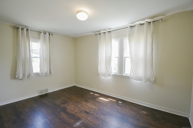 unfurnished room featuring baseboards, visible vents, and dark wood-type flooring