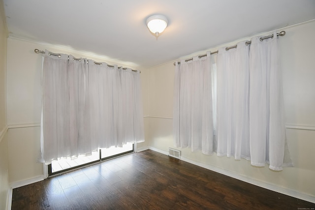 unfurnished room featuring baseboards, visible vents, and dark wood-type flooring