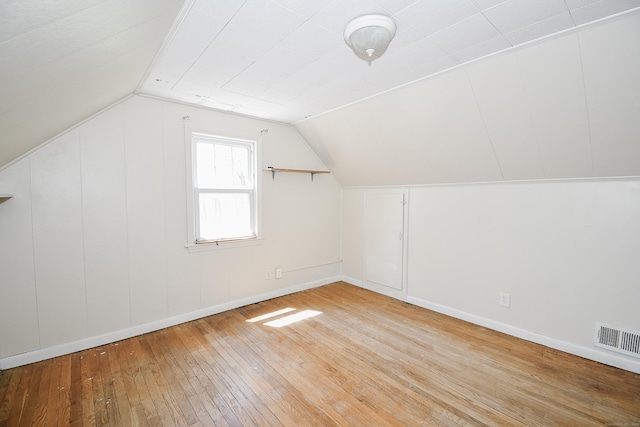 additional living space featuring baseboards, visible vents, lofted ceiling, and hardwood / wood-style flooring