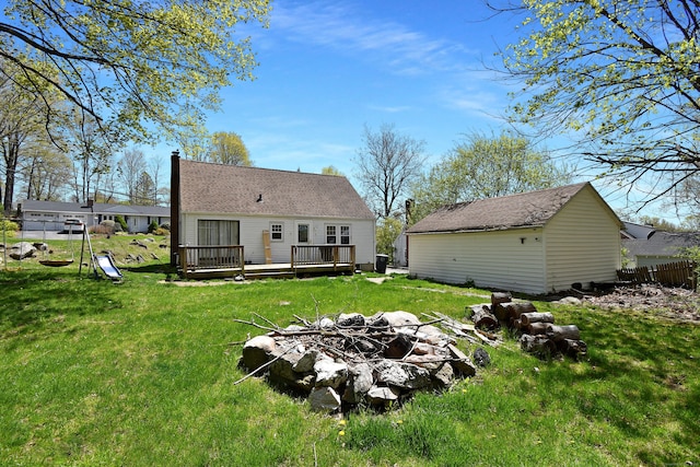 rear view of property with a yard, a fire pit, and a wooden deck