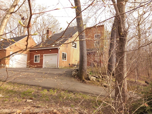 953 Rainbow Trl, Orange, CT 06477 - view of home's exterior featuring a shingled roof, a chimney, concrete driveway, and a garage