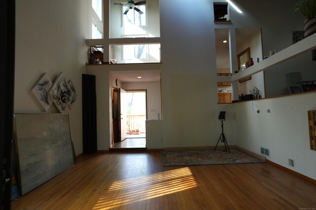 953 Rainbow Trl, Orange, CT 06477 - unfurnished living room with wood finished floors, baseboards, a ceiling fan, and a high ceiling