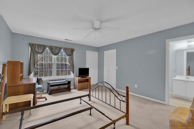 carpeted bedroom featuring ensuite bathroom, a ceiling fan, visible vents, a sink, and baseboards