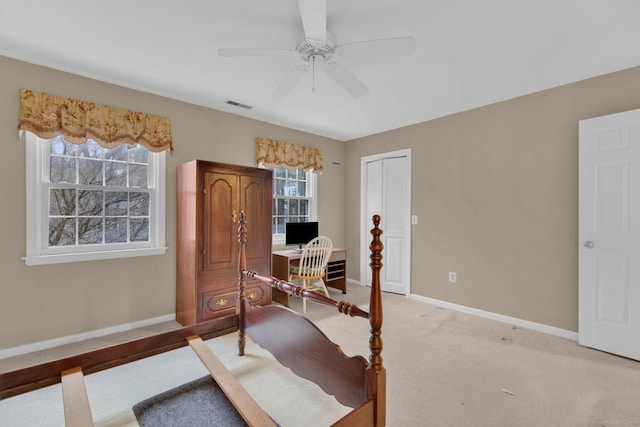 office space featuring light colored carpet, visible vents, baseboards, and a ceiling fan