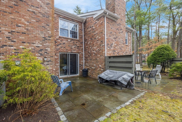 rear view of property featuring a patio area, brick siding, and a chimney