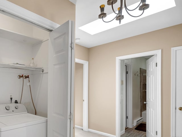 clothes washing area with a baseboard radiator, baseboards, washer / clothes dryer, laundry area, and a notable chandelier